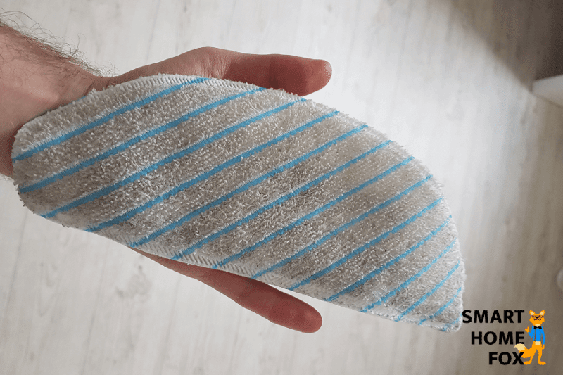 Dirty mop of a typical robot vacuum and mop combo is held in the hands.